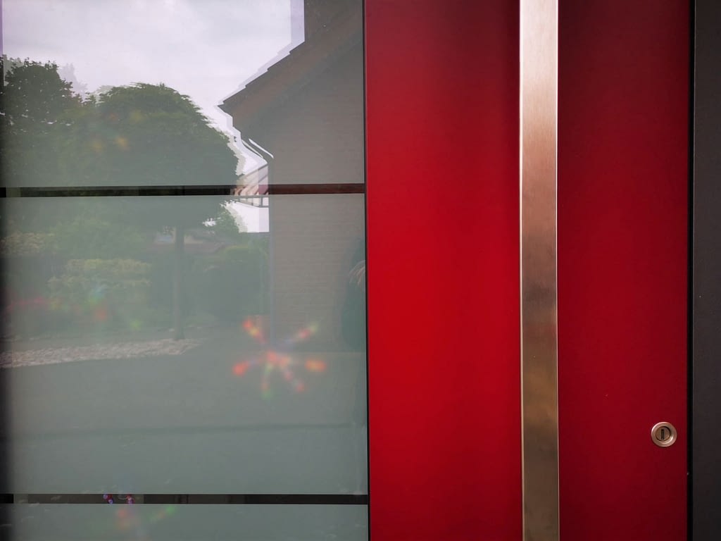 Langer Haustür-Griff aus Stahl vor roter Haustür