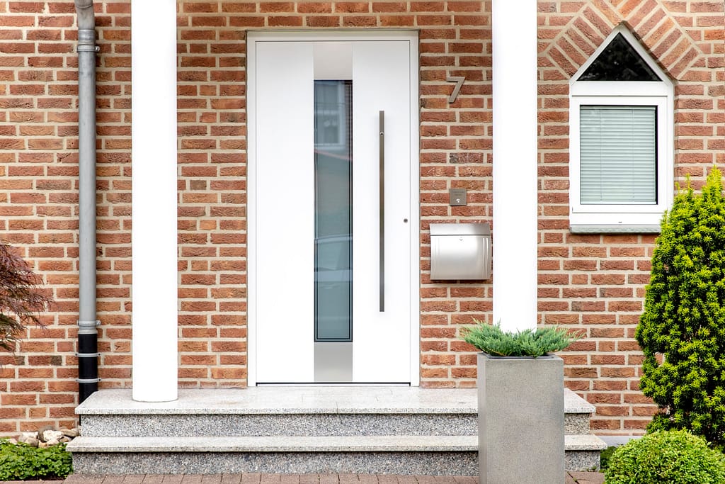 Moderne, weiße Haustür aus Aluminium - flankiert von zwei Säulen